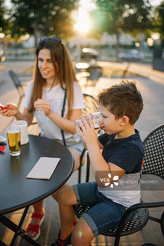 夏季肖像母亲和儿子在户外餐厅露台，莱莱达，西班牙图片素材