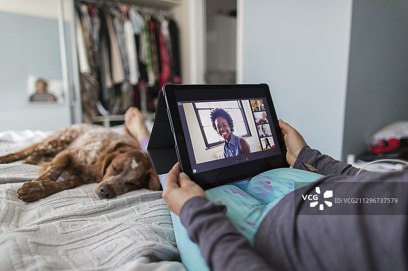 女人用平板电脑和狗狗在床上视频聊天图片素材