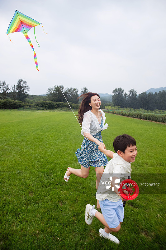 快乐的母子在草地上放风筝图片素材