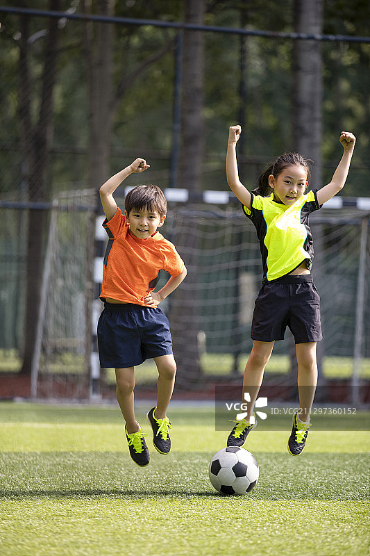 快乐的孩子们在足球场踢足球图片素材
