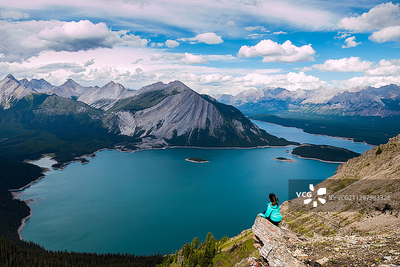 女人坐在山对着天空，Canmore，加拿大的后视图图片素材