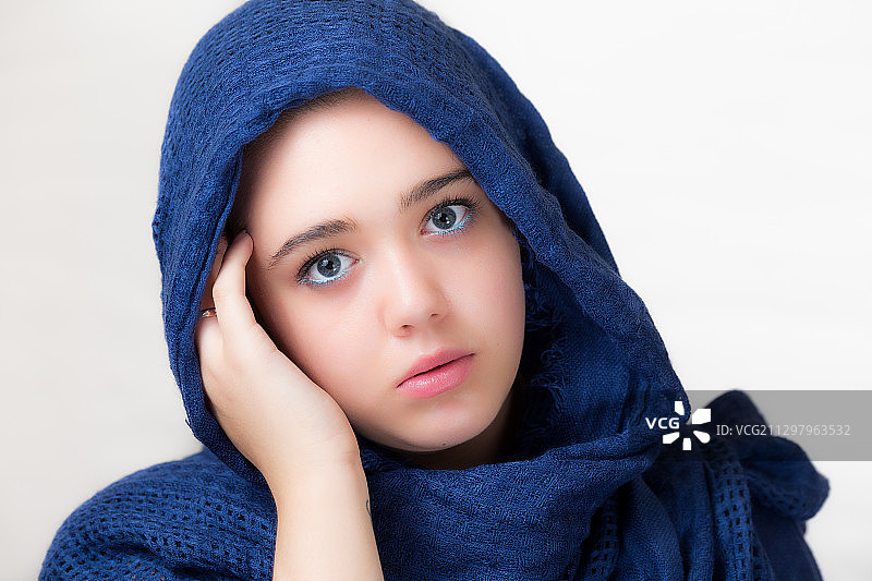 年轻女子戴着蓝色头巾的特写肖像对白色的背景图片素材