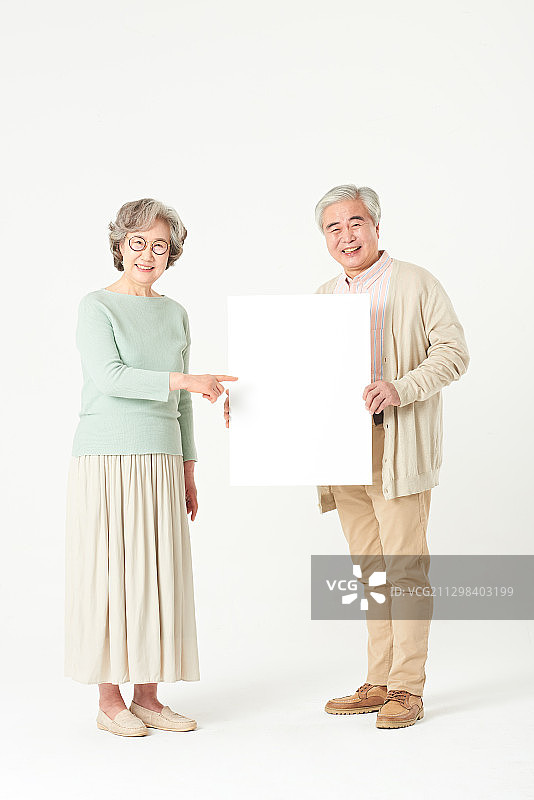 一对老年夫妇站着举着白色的空白横幅图片素材