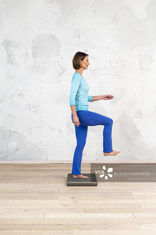 平衡板练习:膝盖和脚跟组合，右膝盖抬高到臀部高度图片素材
