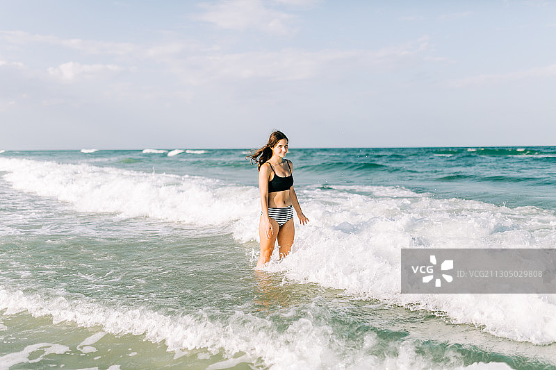 白人少女站在海浪中的海洋，圣奥古斯丁海滩，佛罗里达，美国，美国图片素材