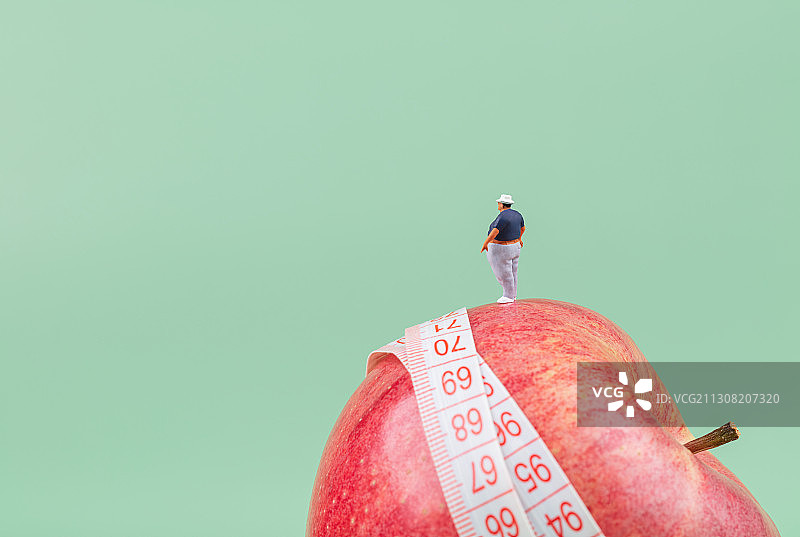卷尺苹果上的一个大肚子大腰围男性胖子图片素材