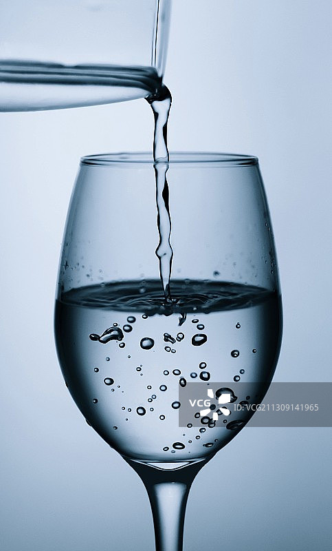特写水倒在酒杯的灰色背景，班加罗尔，卡纳塔克邦，印度图片素材