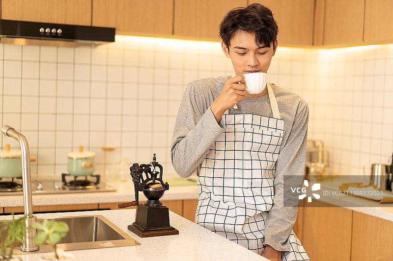 在厨房里喝咖啡的年轻男性图片素材
