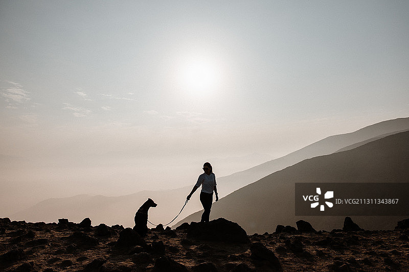 秘鲁拉莫利纳，日落时分，一个女人和一只狗站在岩石上图片素材