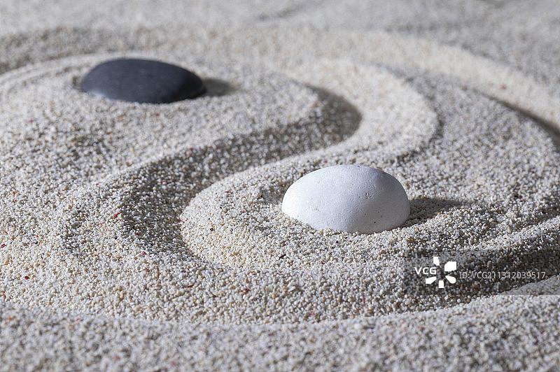 ,沙子上面放着黑白两块石头拼成的太极图案图片素材