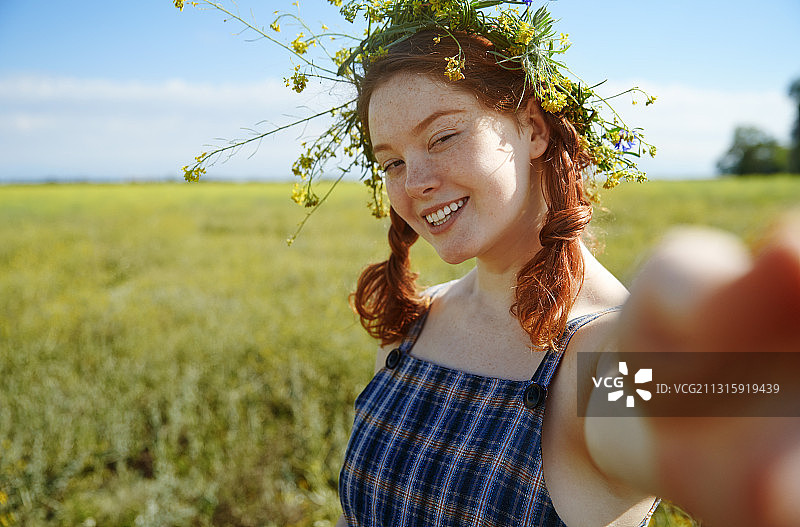快乐的年轻女子戴着花冠在草地上图片素材
