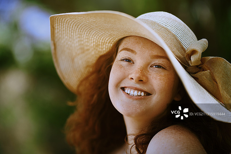 快乐的红发女人，脸上有雀斑，戴着太阳帽图片素材