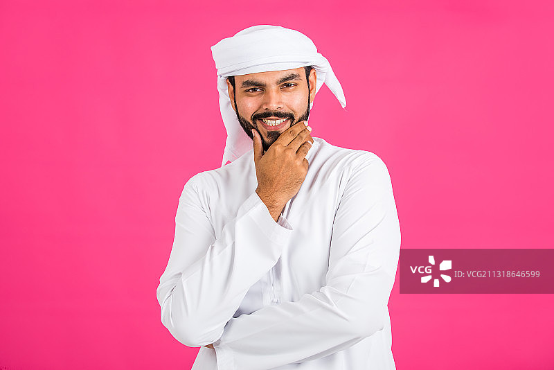 一个穿着传统阿拉伯服装的男人的肖像，背景是粉红色的图片素材