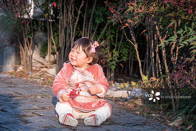 园林里坐在地上玩耍的穿着汉服的小女孩图片素材