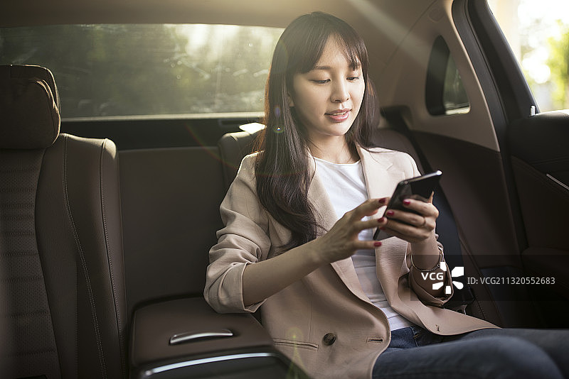 年轻女子在小轿车使用智能手机图片素材