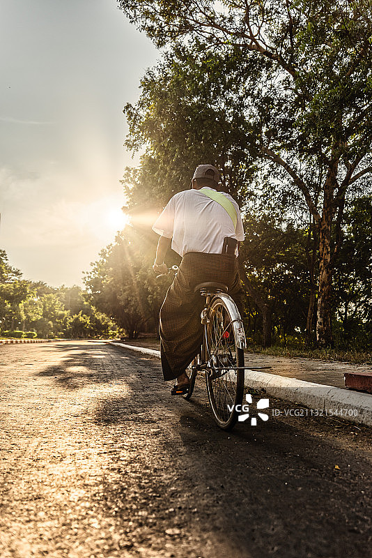 缅甸，老蒲甘，男人骑着自行车在路上的背影图片素材