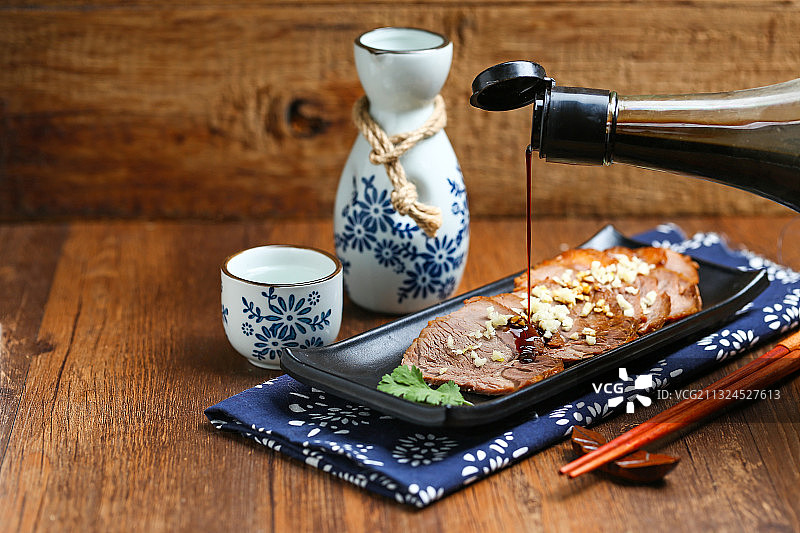 黑色盘子里的酱牛肉和白酒酒壶酒杯酒具放在木桌上图片素材