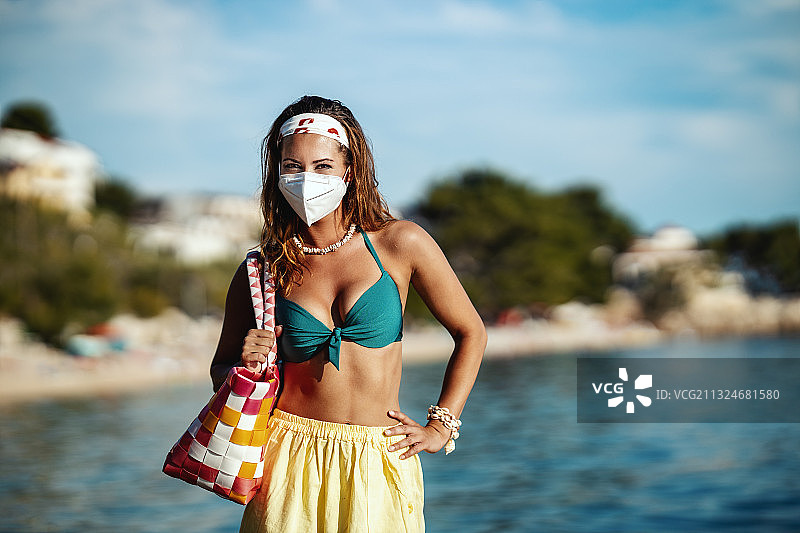 克罗地亚马卡斯卡，一名妇女戴着医用口罩站在海滩上图片素材
