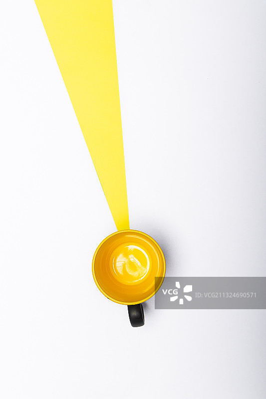 直接上方拍摄的黄色光马克杯与射线的黄色在白色的背景图片素材