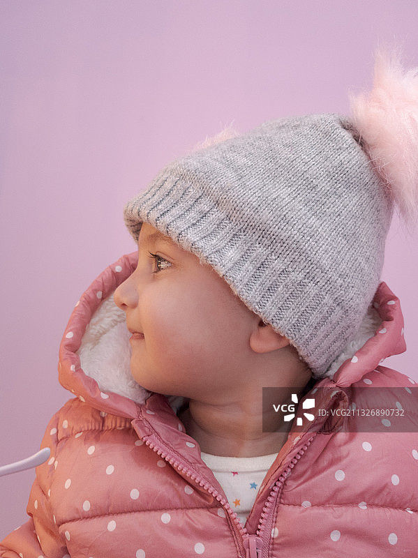 可爱的小女孩穿着温暖的衣服，背景是粉红色，韩国图片素材