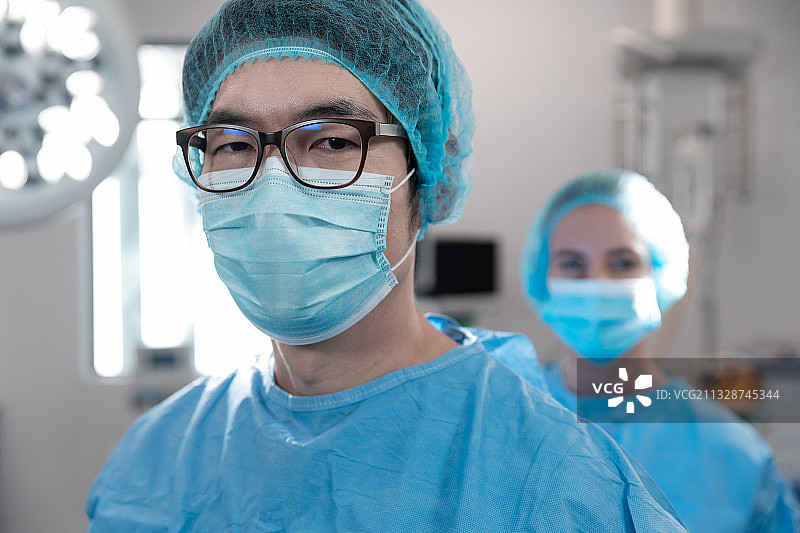 混血男外科医生戴着口罩站在手术室的肖像图片素材