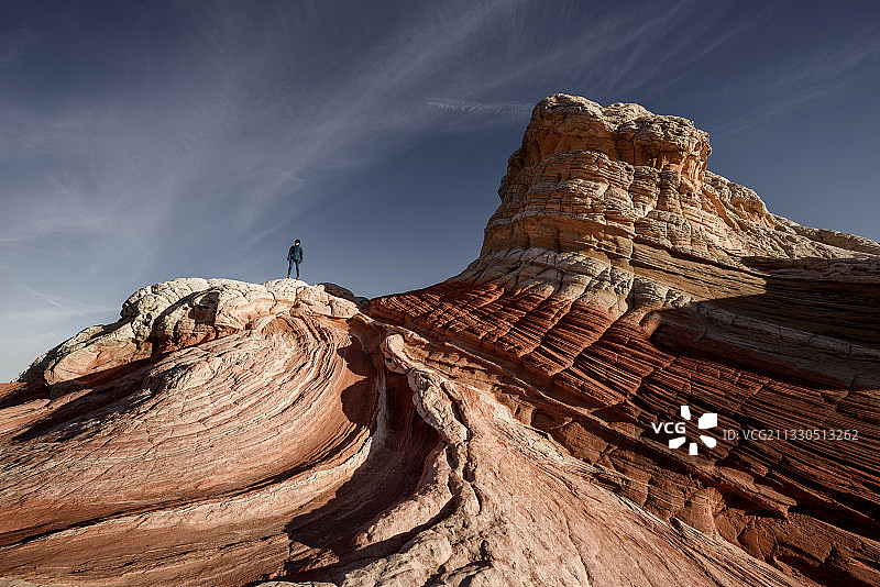 女人站在岩石上，背靠天空图片素材