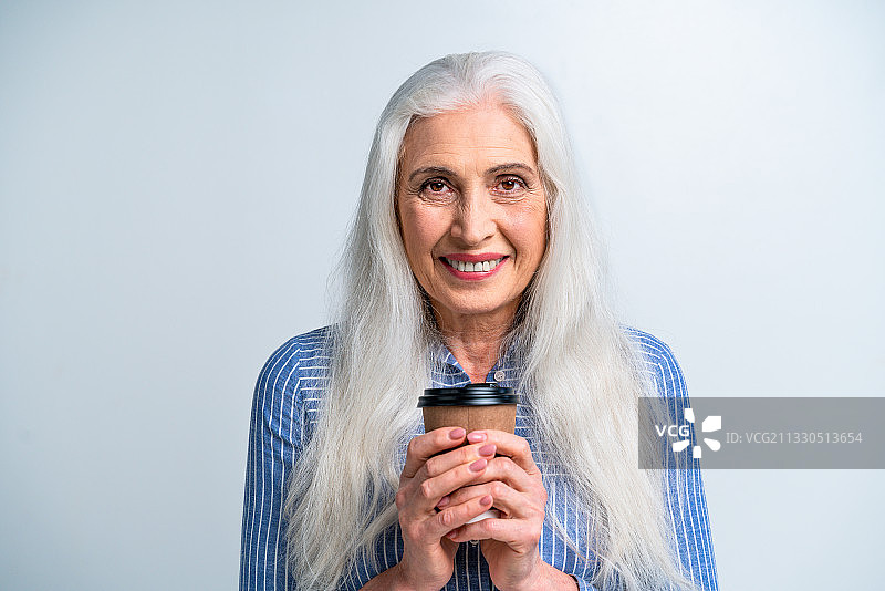 一个年长的女人拿着一杯咖啡的肖像图片素材