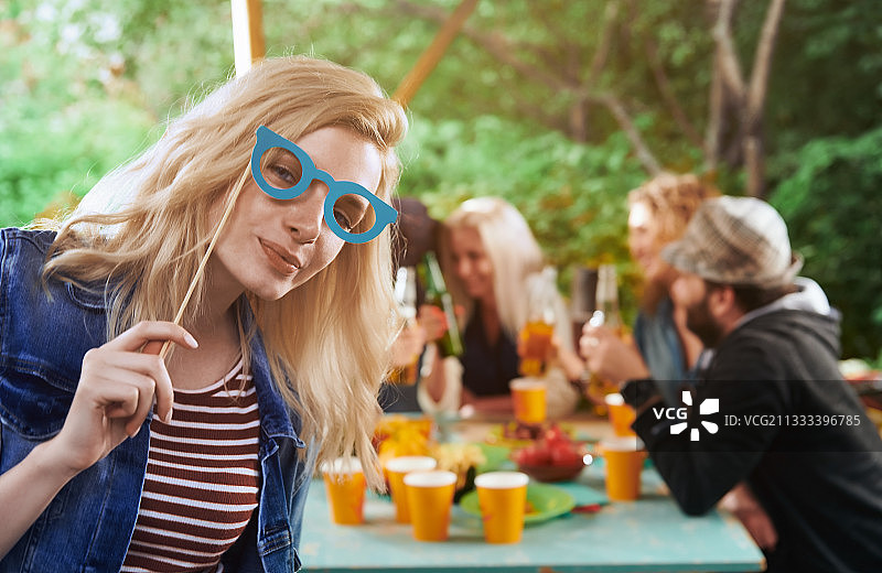 无忧无虑的金发女人戴着狂欢节面具，和朋友们在游园会上玩得很开心图片素材