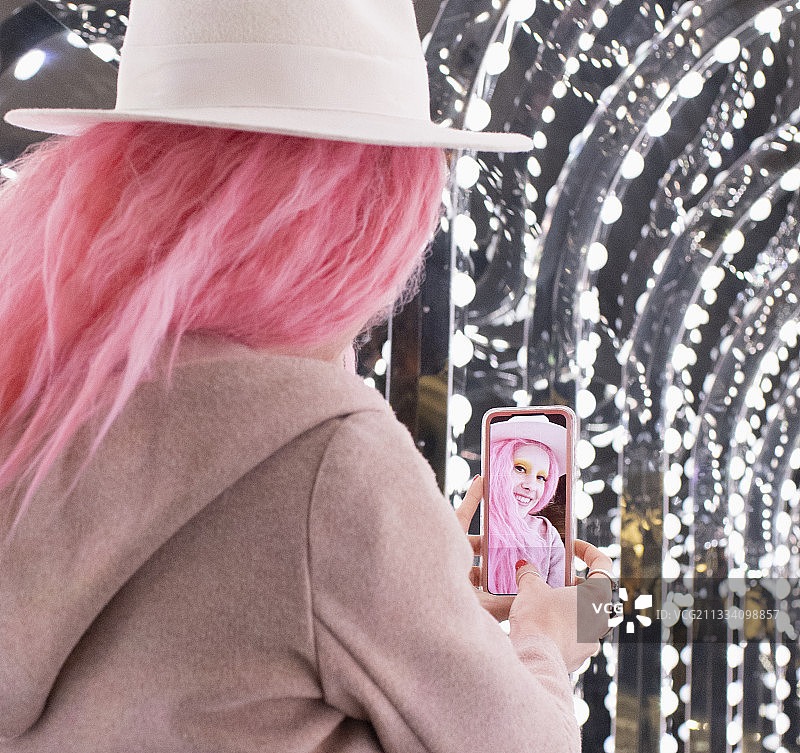 漂亮时髦的粉红头发的女人在灯光下自拍图片素材