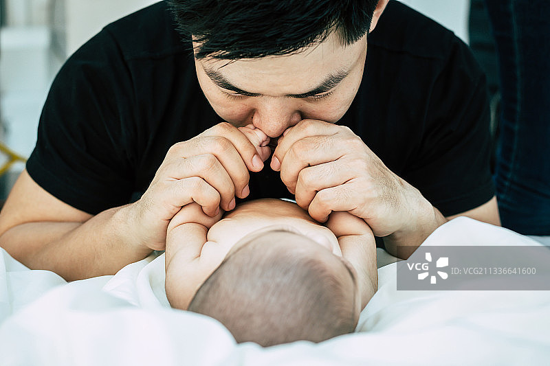 一位年轻的亚洲父亲正在嗅他刚出生的孩子图片素材