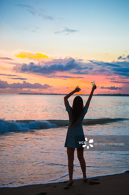女人在日落时站在海滩上的背影图片素材