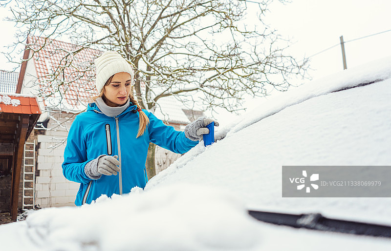一个女人在冬天刮掉她汽车前车窗上的冰，觉得有点烦图片素材