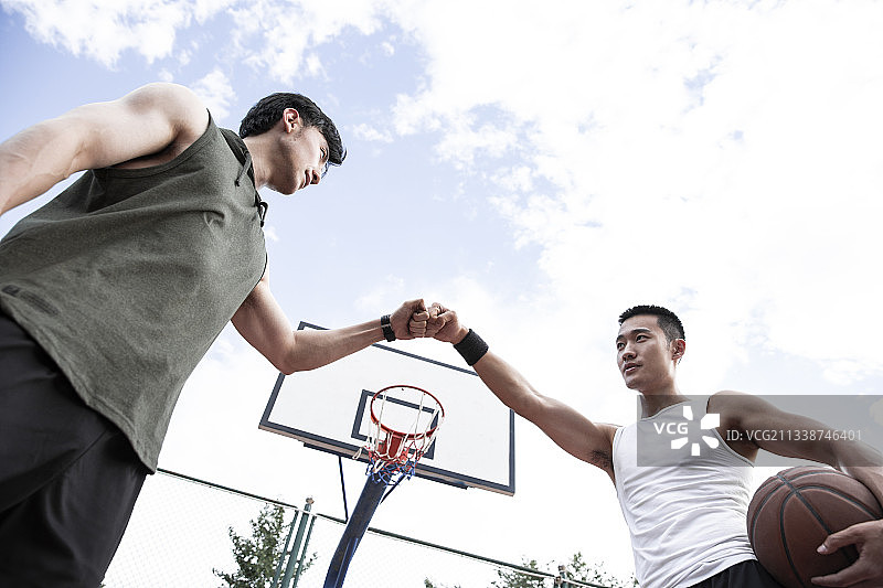 两个青年男子在学校篮球场打篮球顶拳图片素材