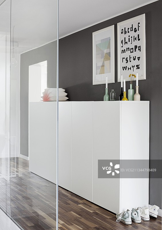 半高的白色橱柜在深灰色的墙前，在走廊透明的玻璃隔断后图片素材