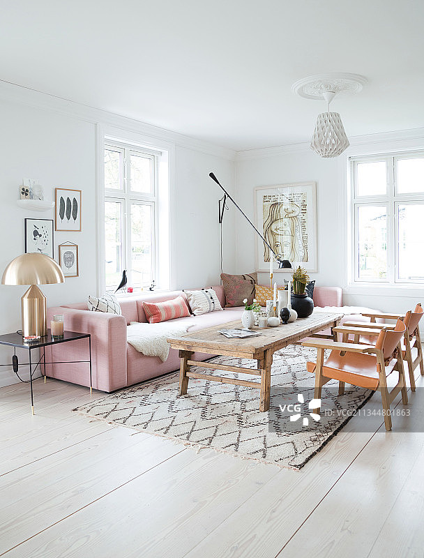 客厅里粉红色的软垫套间，金色的台灯，质朴的咖啡桌和皮椅图片素材