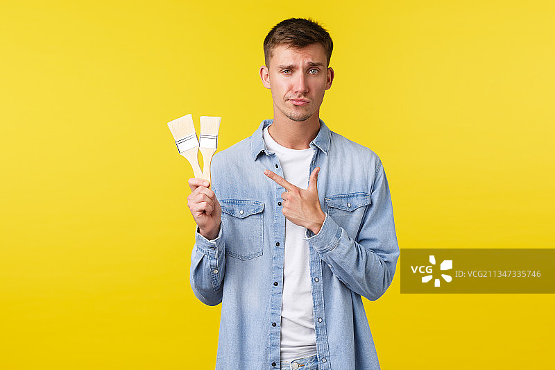年轻男子手持信用卡，站在黄色背景下图片素材