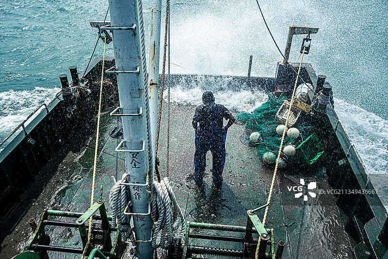 风浪中的拖网渔船渔民大叔，安全操作的标语写在桅杆显眼位置图片素材