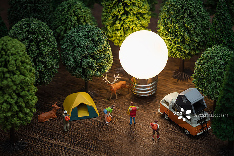 微缩创意发亮的灯泡森林里营地露营的旅行者图片素材