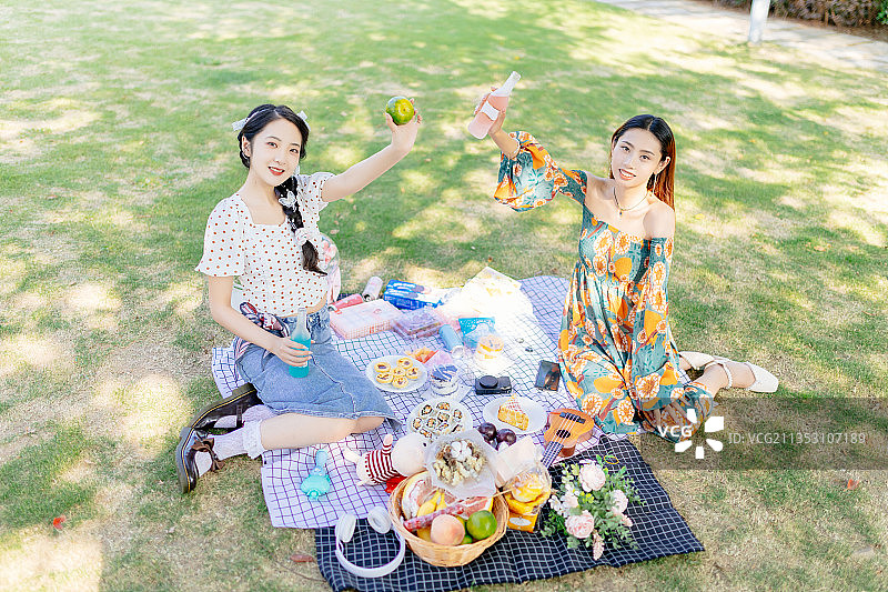 两个亚洲青年美女闺蜜在户外野餐垫上野餐图片素材