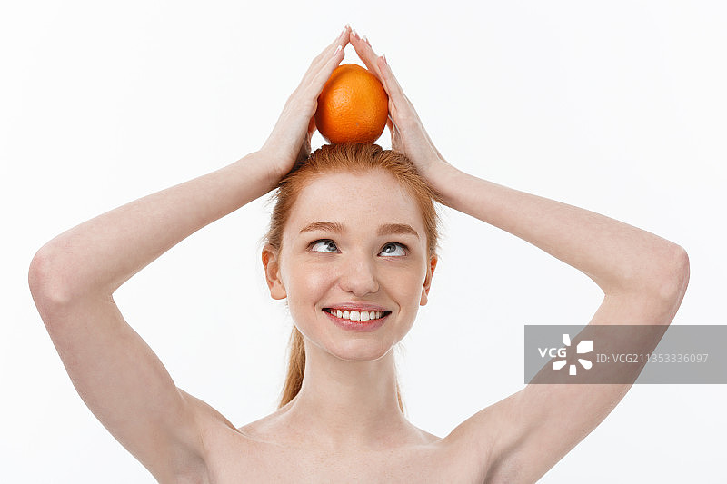 年轻女子拿着橘子在白色背景下图片素材