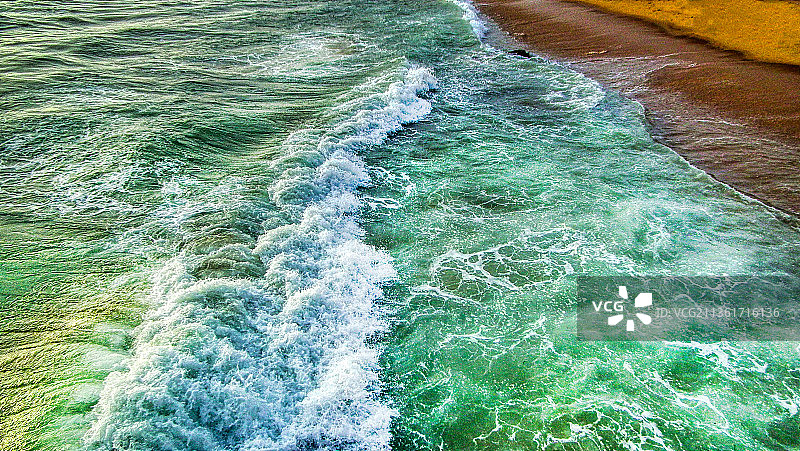 进入海岸，海浪拍打海岸的高角度视角图片素材