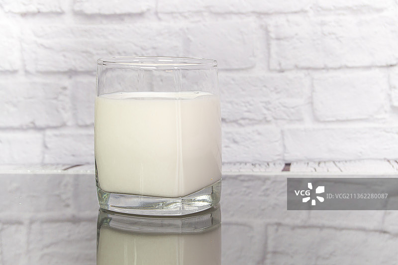牛奶在一个透明的杯子上的桌子上，倒影图片素材