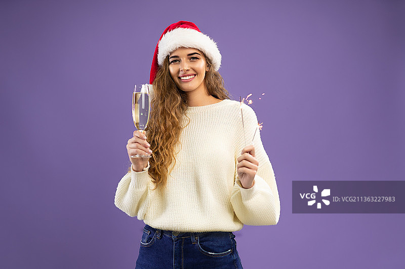 快乐女孩的肖像，戴着圣诞老人的帽子，喝着香槟图片素材