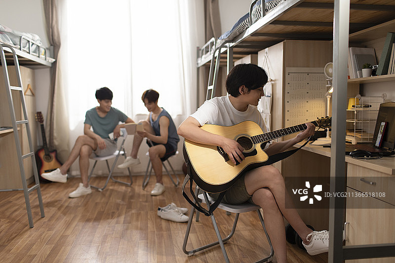 年轻大学生在宿舍弹吉他图片素材