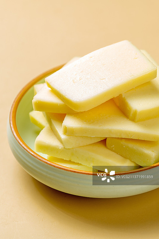 一盘奶豆腐摆放在黄色背景上图片素材