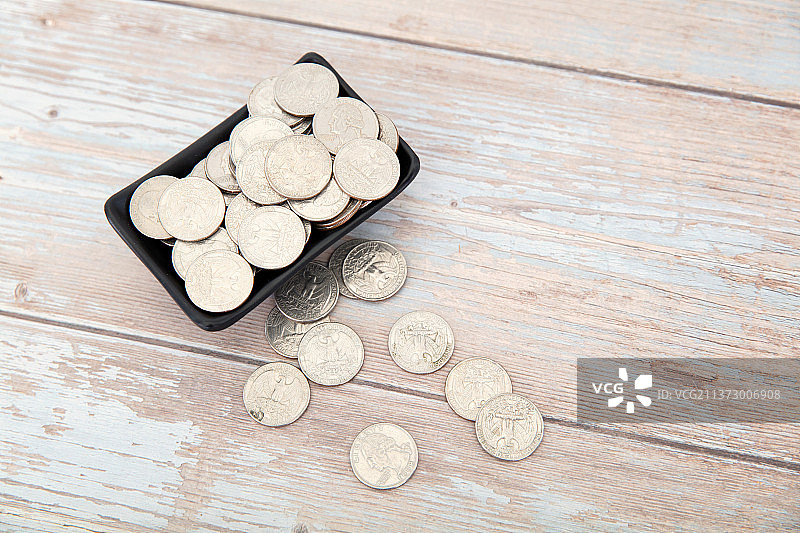 桌子上盛满美元硬币的小碟子和散落的硬币图片素材