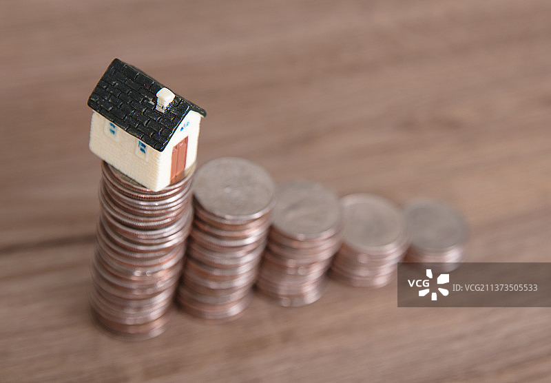 一排递减的美元硬币和一个硬币上的小房子模型图片素材