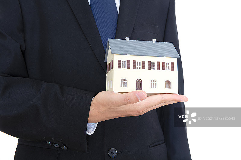 身穿黑色西服打着领带的男性手里捧着一个小房子模型图片素材