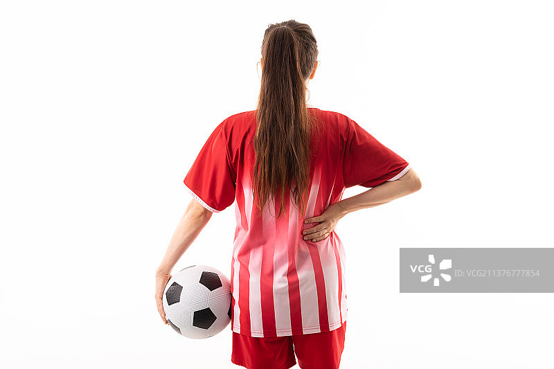 白人年轻女足球运动员的后视图与球和手在臀部对白人背景图片素材