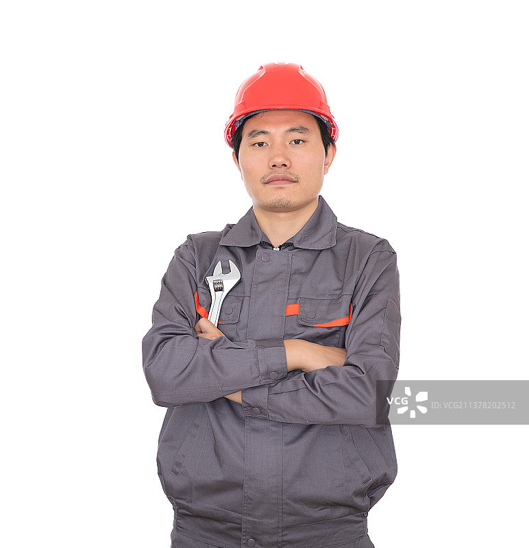 头戴红色安全帽手拿活口扳子的工人抱着胳膊站在白背景前图片素材
